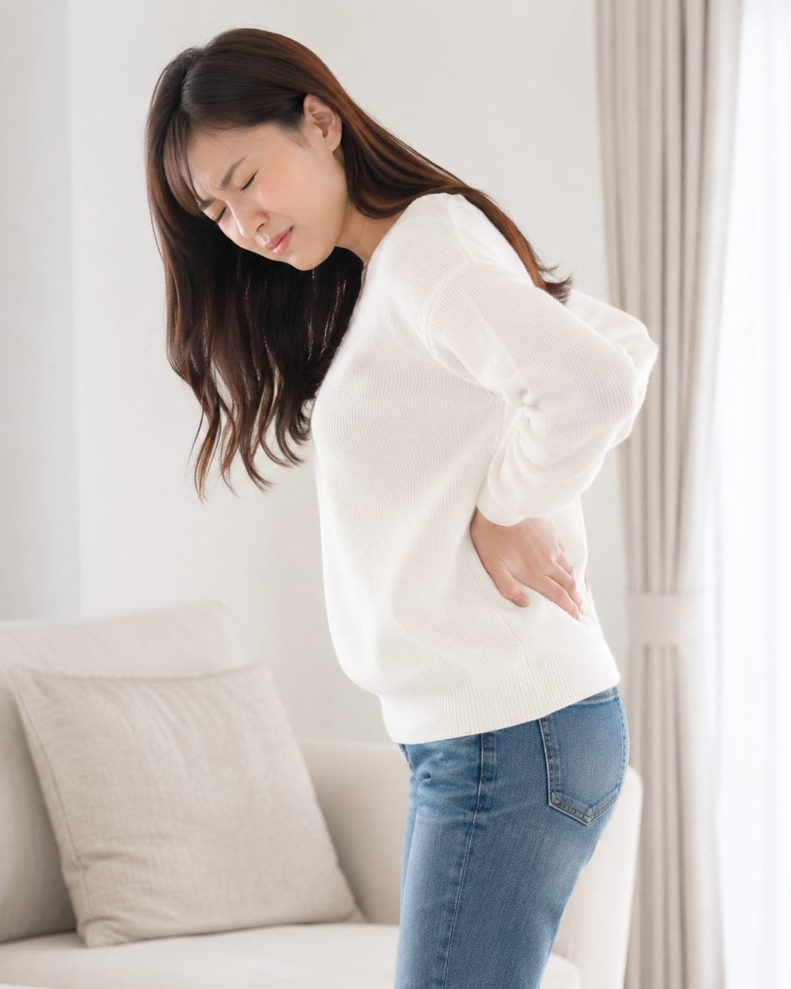 腰を押さえて立つ女性(イメージ)