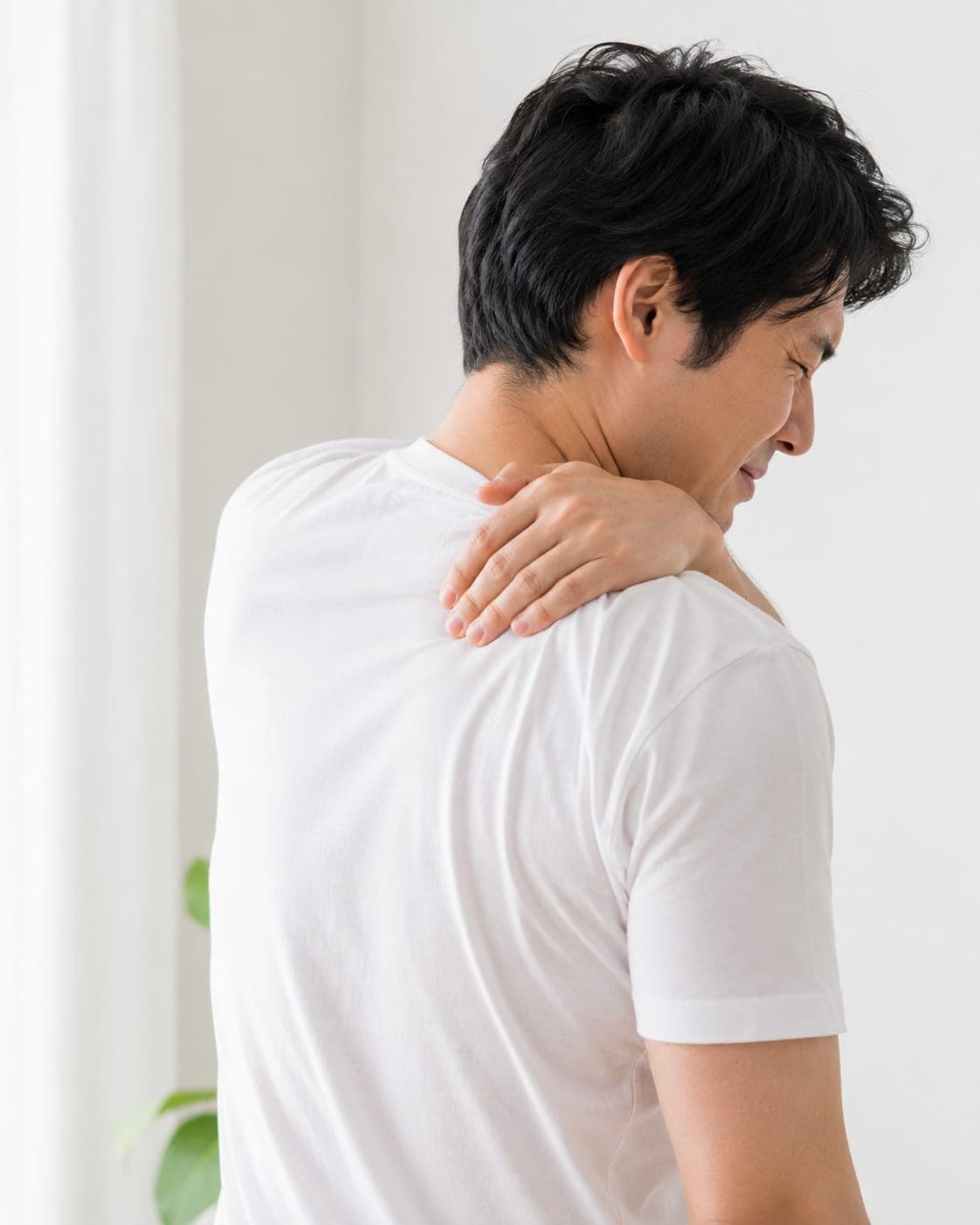 後ろ姿で肩を押さえる男性(イメージ)
