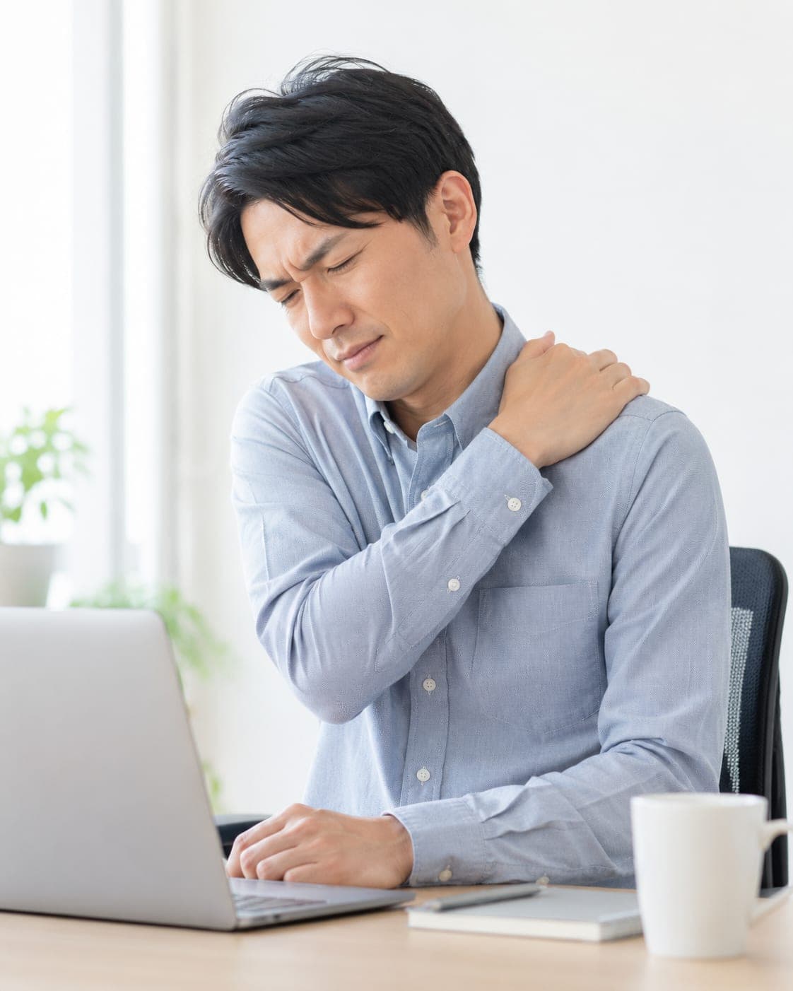 パソコン作業中に肩を押さえる男性(イメージ)