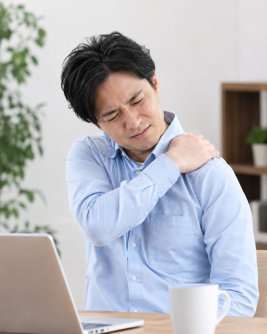 パソコン作業中に肩を押さえる男性(イメージ)