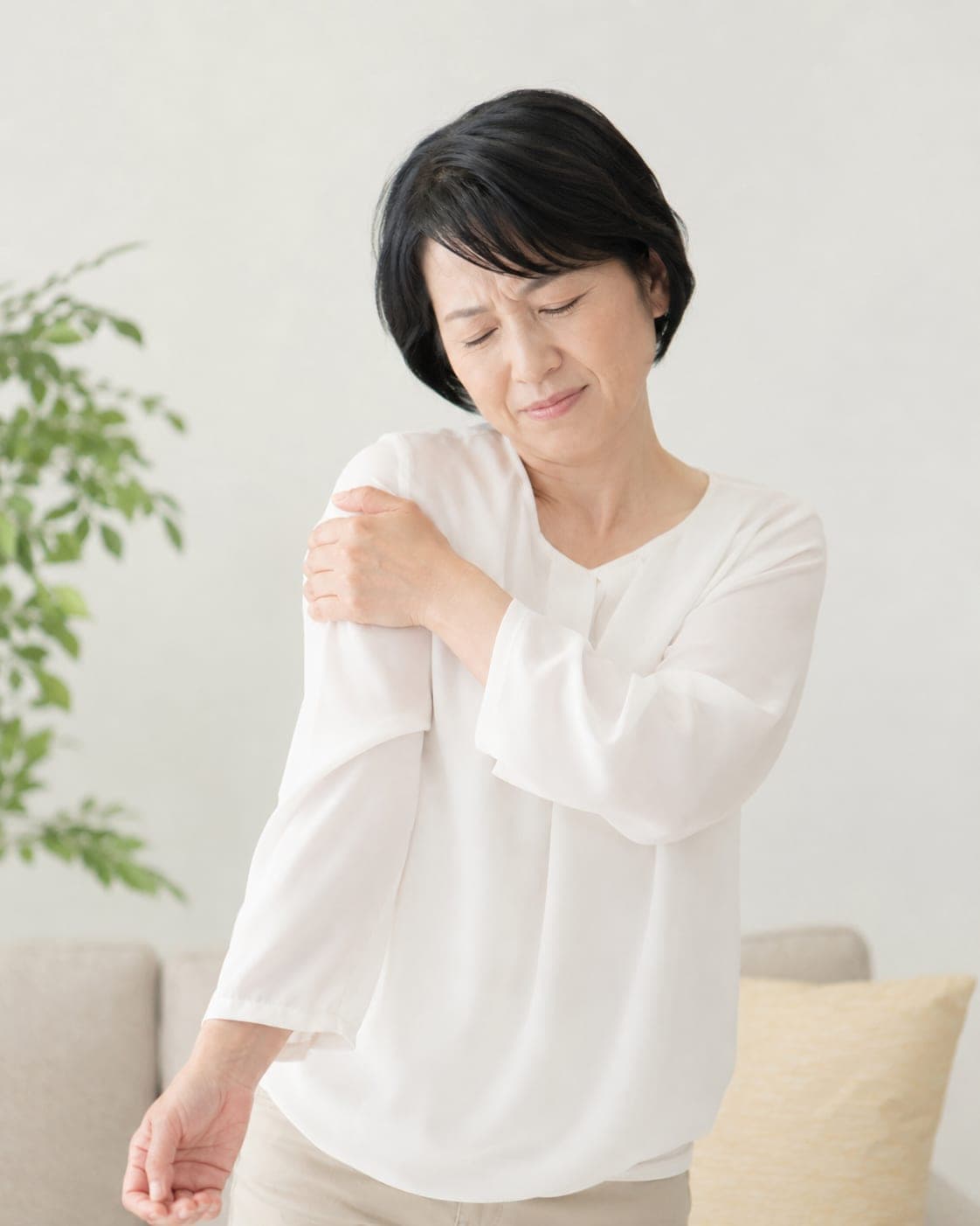 肩を押さえる年配の女性(四十肩・五十肩のイメージ)