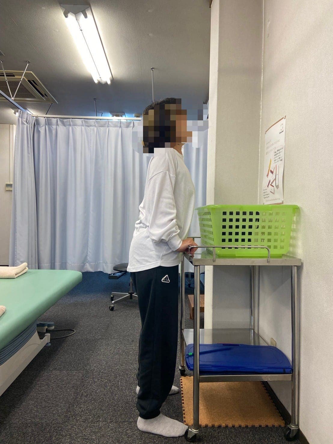 清水接骨院の施術室で、患者さんの立ち姿勢を横から確認している様子