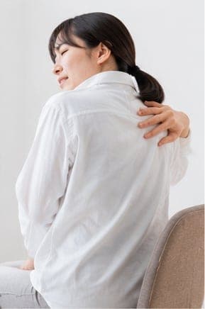 後ろ姿で肩を押さえる女性(イメージ)