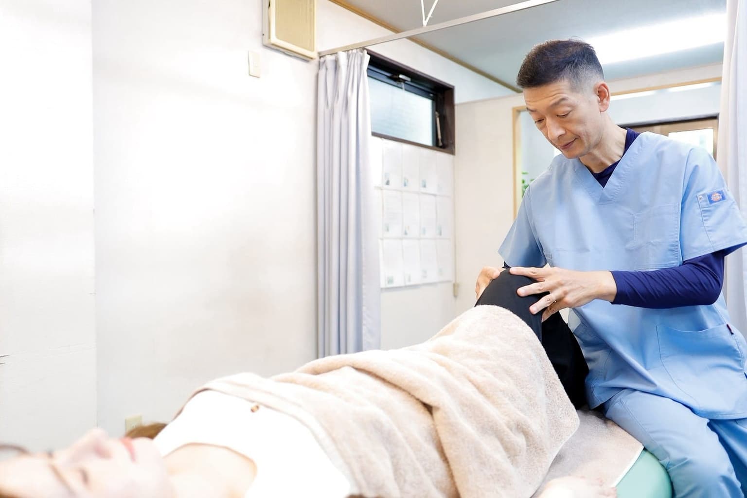 ベッドに横になった患者さんの膝の状態を確認しながら施術する清水接骨院の院長